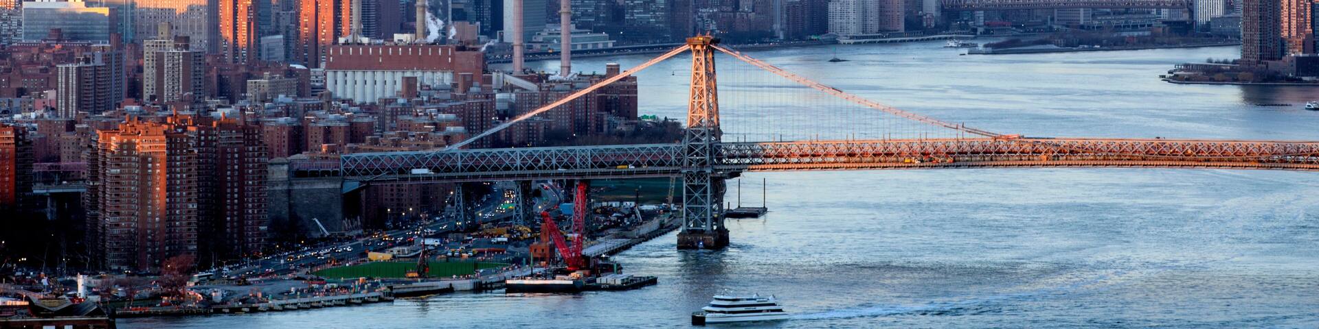 New York City skyline with Williamsburg bridge seen at dusk from Brooklyn with sun reflecting in skyscrapers