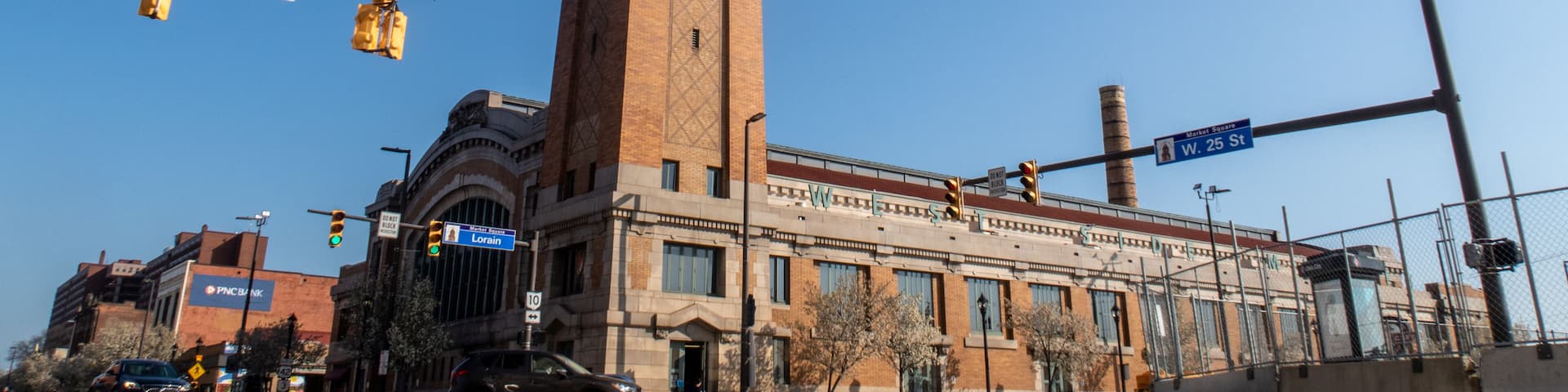 A tall brick tower with a clock, surrounded by buildings and traffic lights.