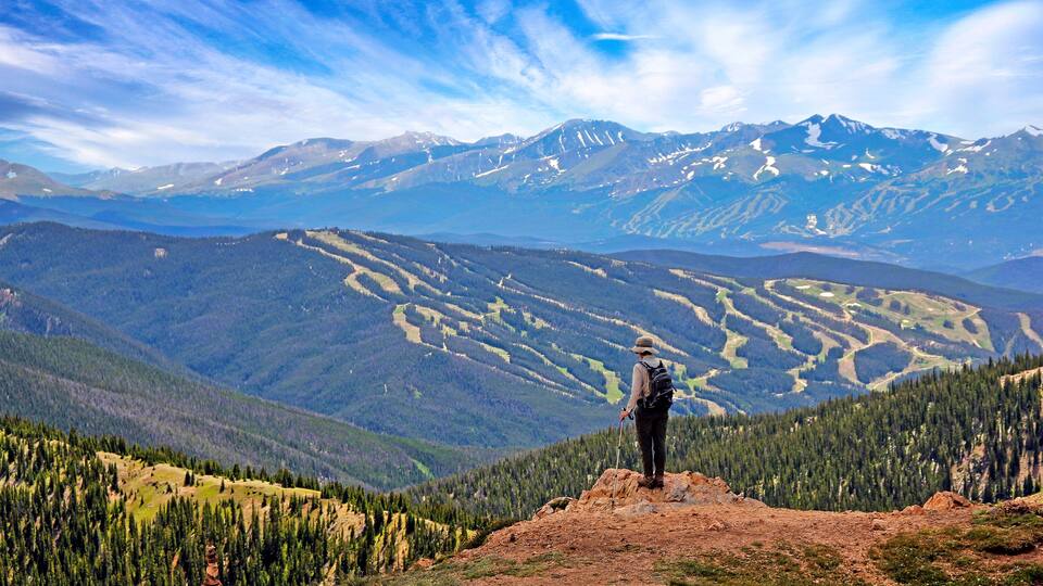 Hiker in Colorado above 12,000 feet on the West Ridge Trail near Loveland Pass with ski runs of Keystone in the background
