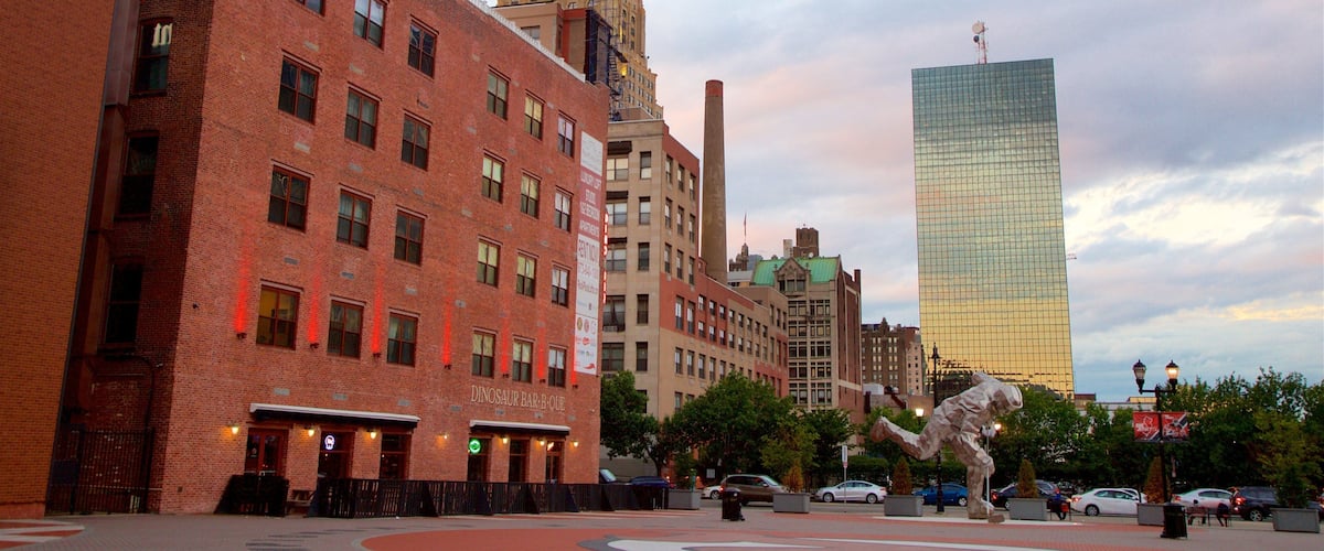 A city square with a dinosaur statue, brick buildings, and a modern skyscraper.