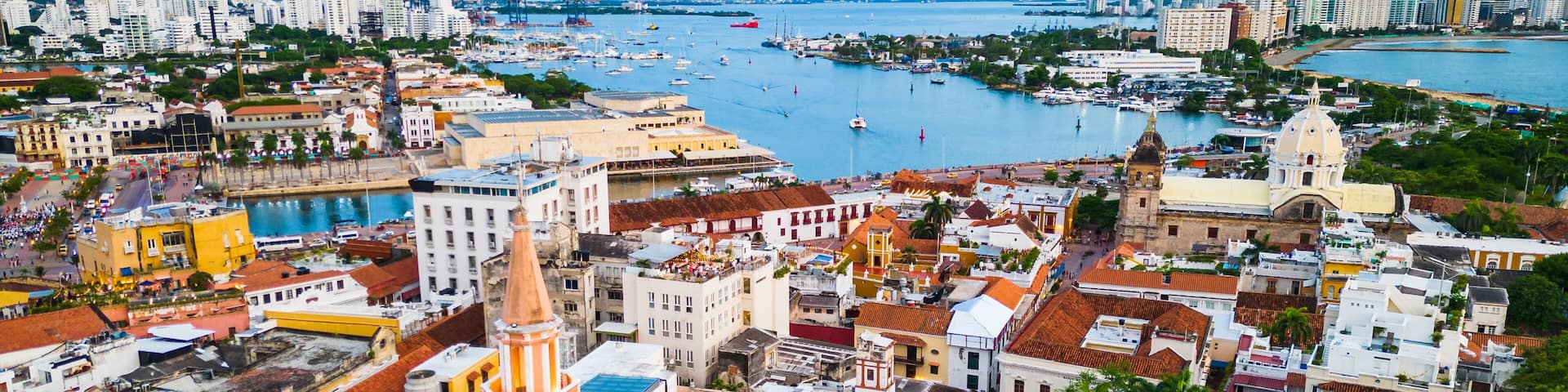A coastal cityscape with historic buildings, a marina, and a prominent church tower.