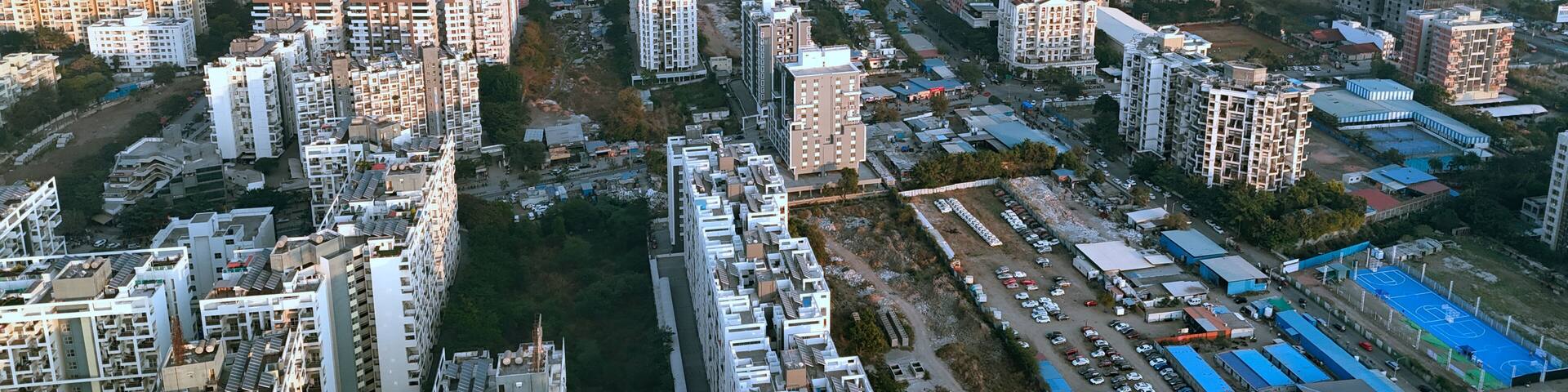 A densely packed urban area with numerous high-rise residential buildings and a large industrial zone with warehouses and a sports court.