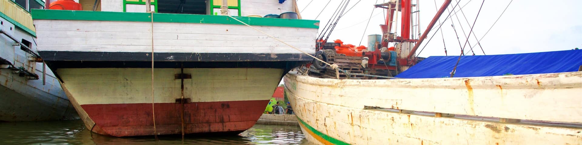 Two boats docked at a harbor with a building in the background.