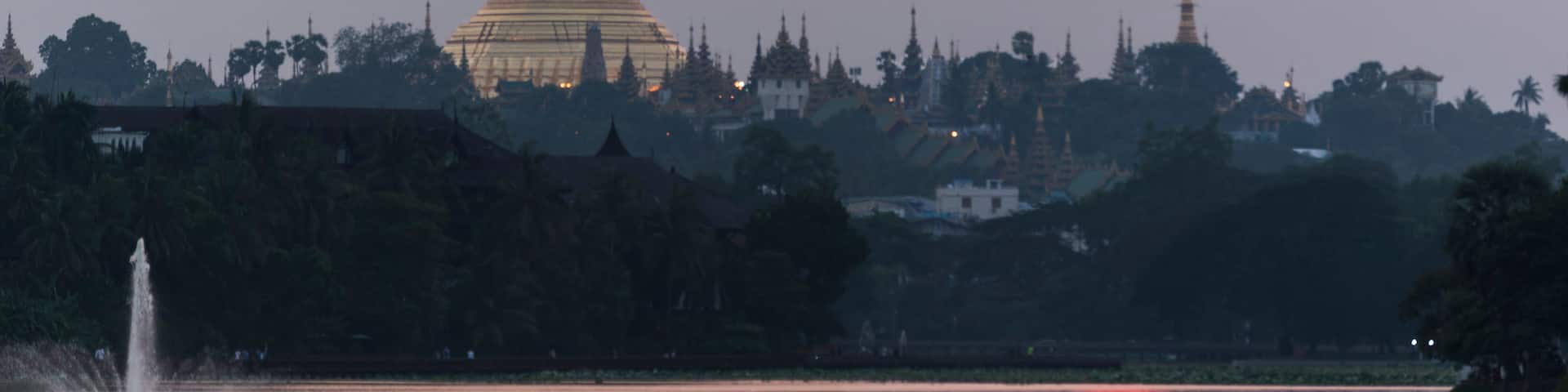 A pagoda with a reflection in a body of water during sunset.