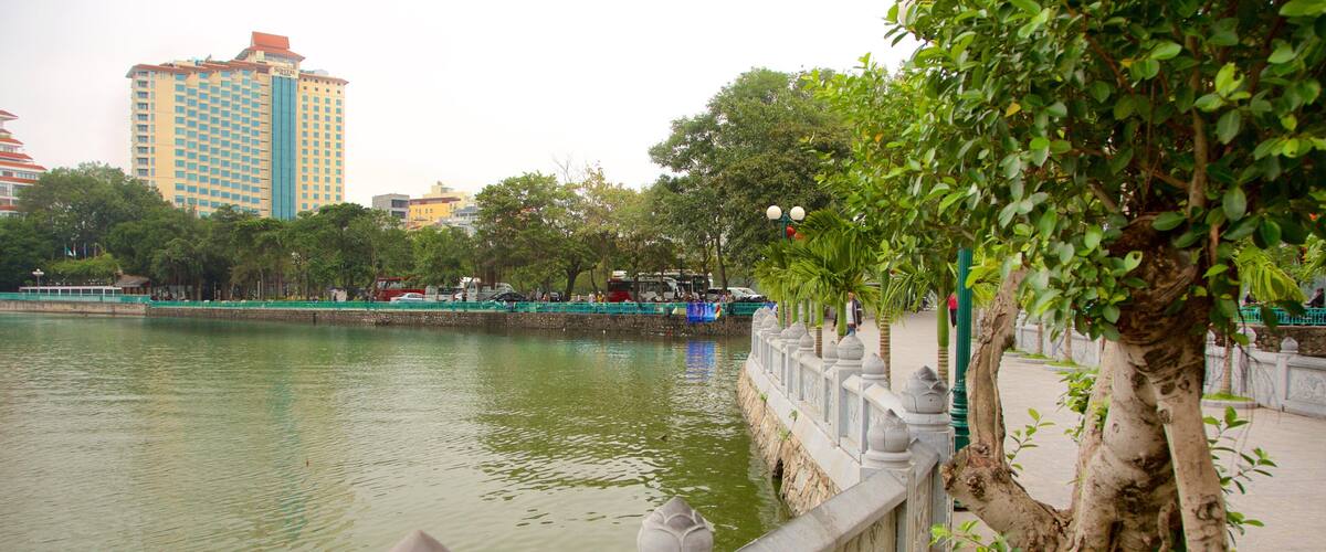 A river with a stone railing, trees, and a building in the background.