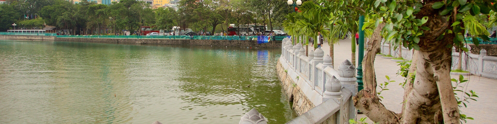 A river with a stone railing, trees, and a building in the background.