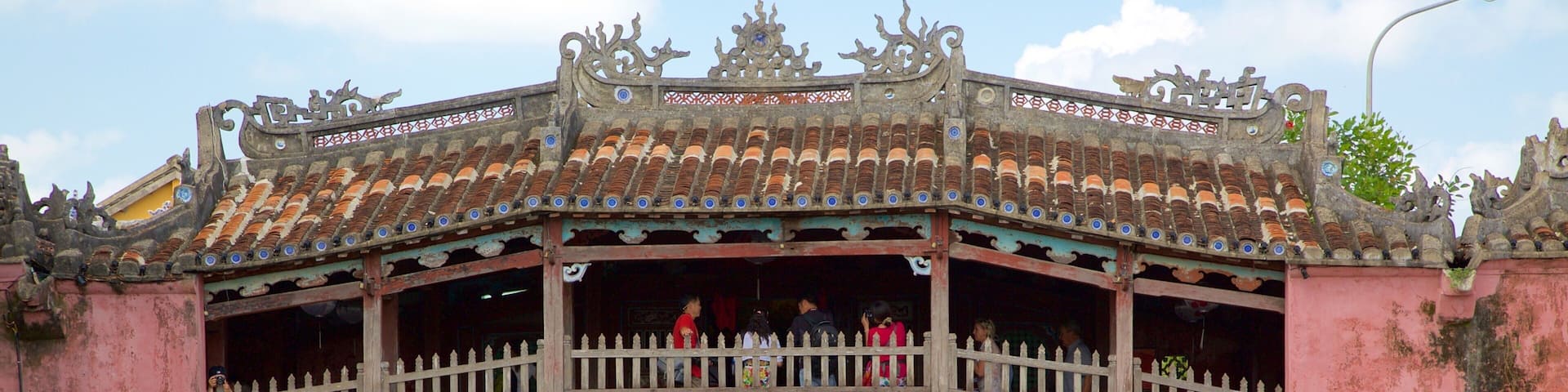 A traditional bridge with ornate railings and a tiled roof spanning over a canal.