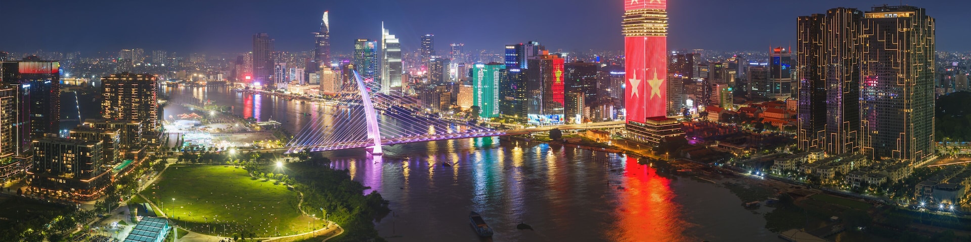 HO CHI MINH CITY, VIETNAM: Aerial view of Ba Son bridge and city center skyline illuminated with red national flag LED light at night