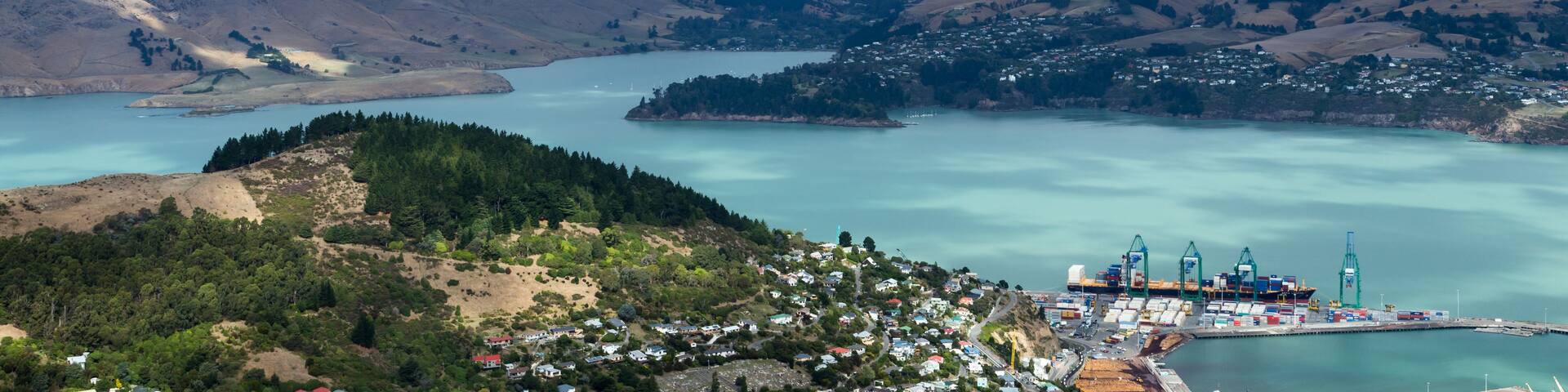 A coastal town with a harbor, surrounded by hills and a large body of water.