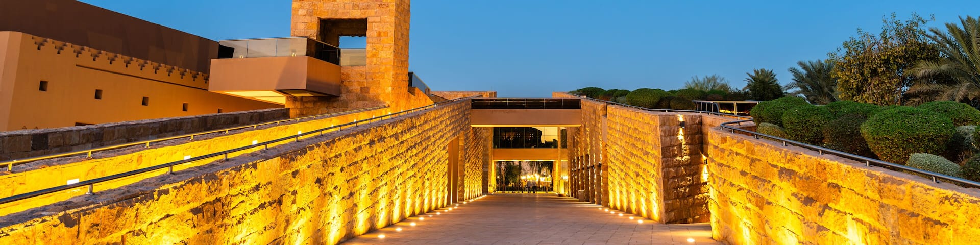 Sheikh Muhammad ibn Abd al-Wahhab Mosque with a beautifully illuminated stone tower and walkway in Diriyah, Riyadh, Saudi Arabia during blue hour