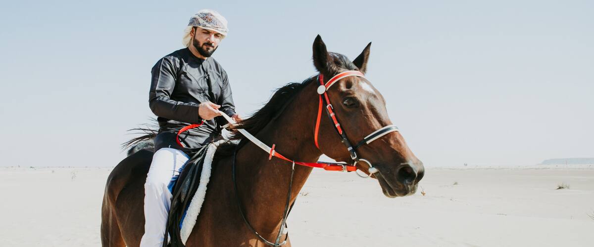 Arabian man with traditional clothes riding his horse