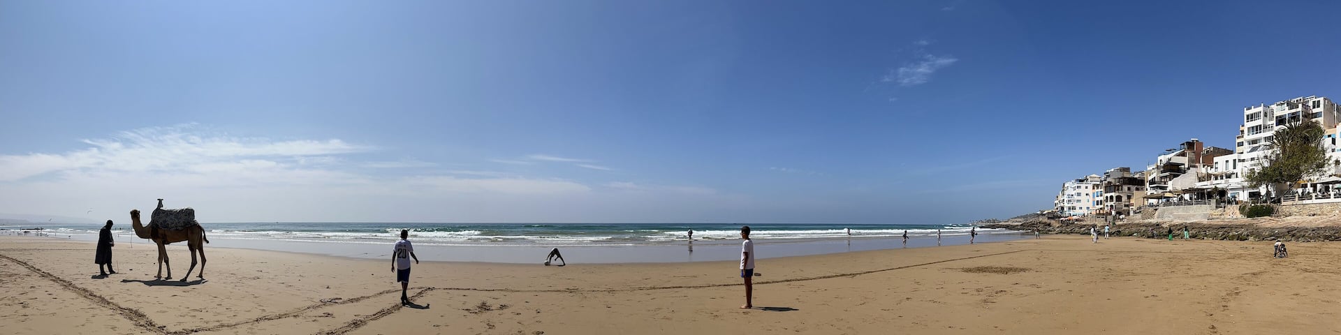 Morocco, Africa: panoramic view of a camel and boys playing soccer on the beach of Taghazout, small fishing village, whose inhabitants are mostly of Berber origin, near Agadir in southwestern Morocco