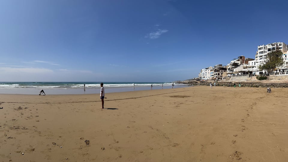 Morocco, Africa: panoramic view of a camel and boys playing soccer on the beach of Taghazout, small fishing village, whose inhabitants are mostly of Berber origin, near Agadir in southwestern Morocco