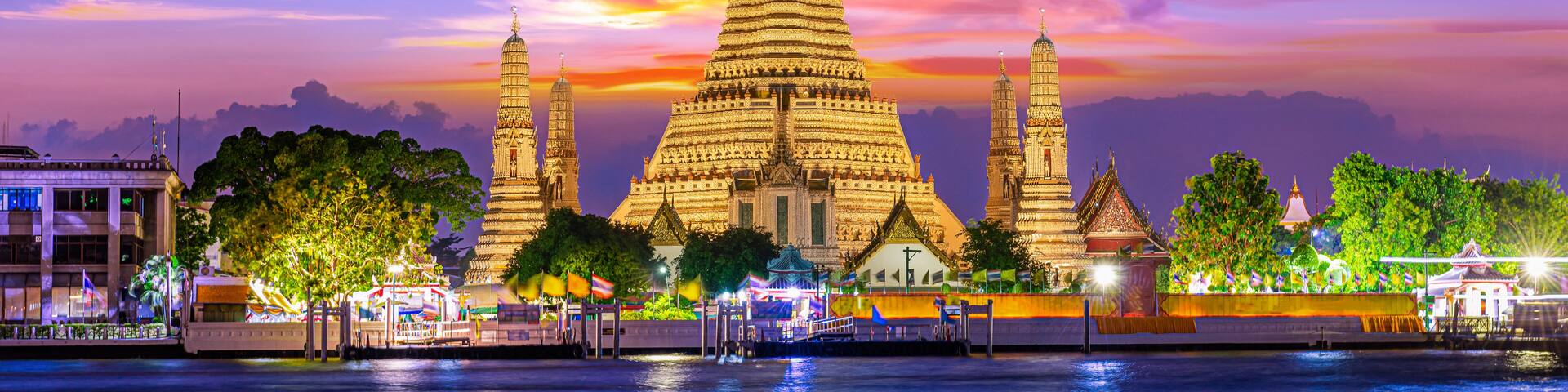 A large, intricately designed temple with multiple spires, set against a vibrant sunset sky.