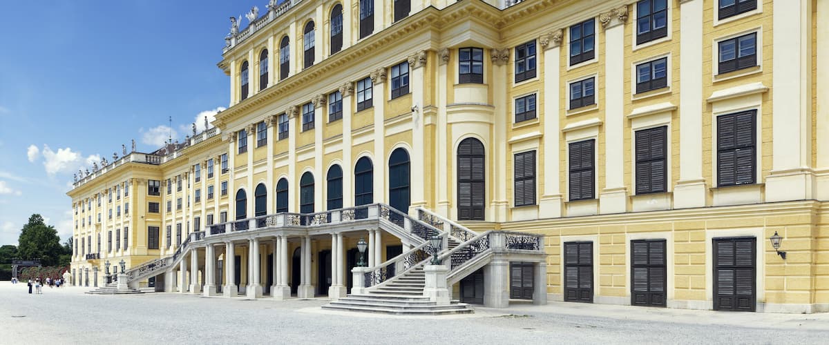 Un edificio clásico imponente con esculturas ornamentadas, una escalera central y una fachada simétrica.