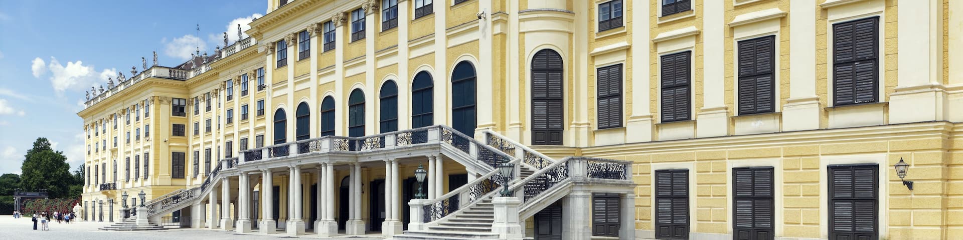 A grand classical building with ornate sculptures, a central staircase, and a symmetrical facade.