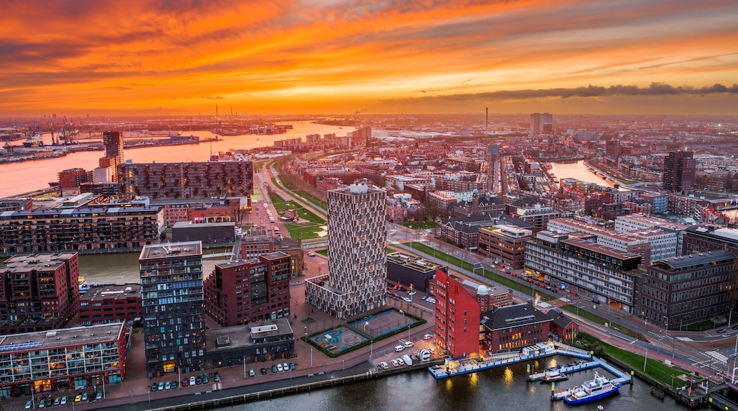A cityscape at sunset with a river, modern buildings, and a distinctive tower.