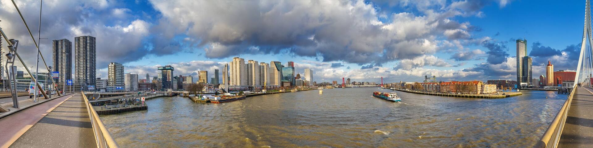 A river with a bridge, tall buildings, and a boat.