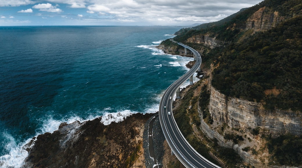 Una autopista costera serpentea a lo largo de un acantilado, con vistas al océano.