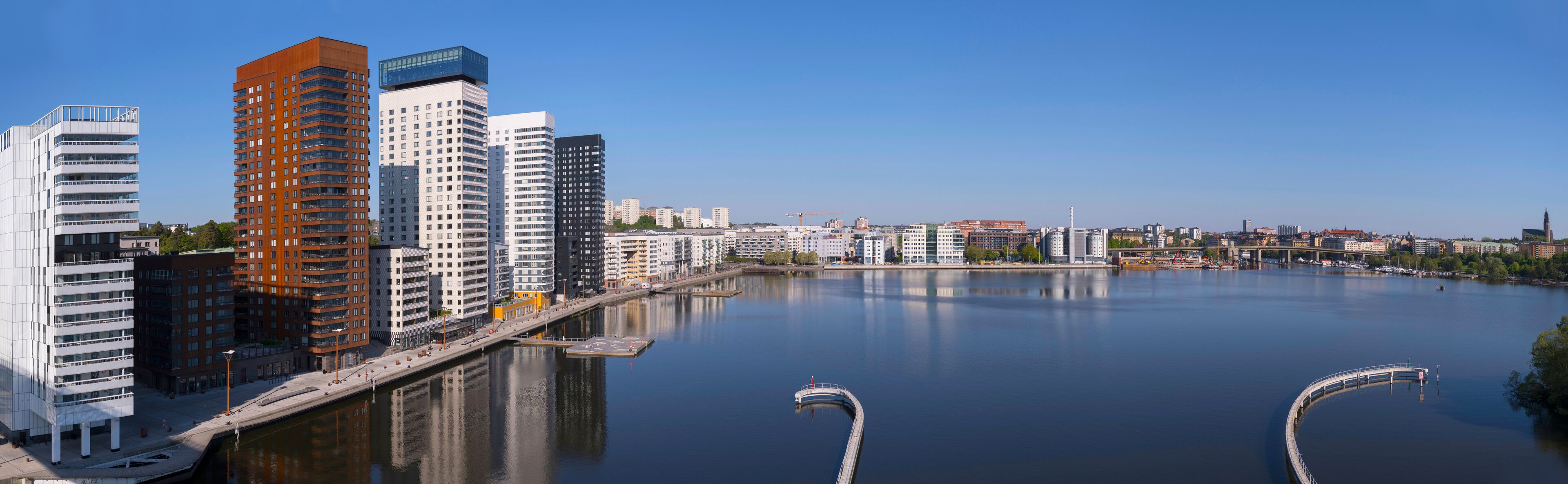 Train bridge view at the bay Årstaviken, apartment skyscrapers reflecting and a tug boat passing bridge, a tranquil early sunny spring day in Stockholm