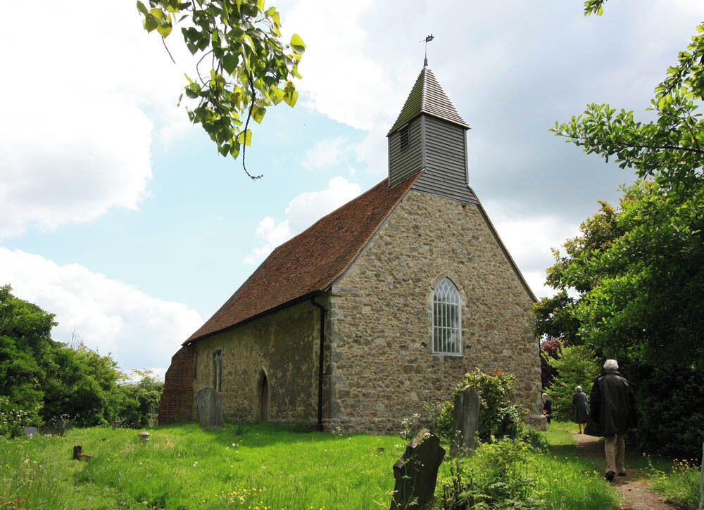 A stone church with a pointed steeple and a large arched window.