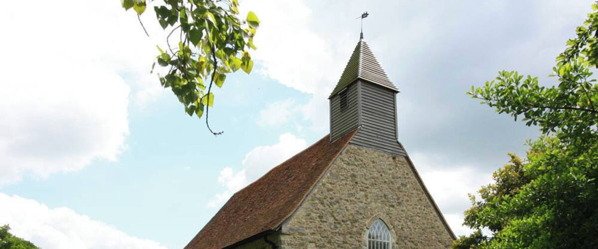 A stone church with a pointed steeple and a large arched window.