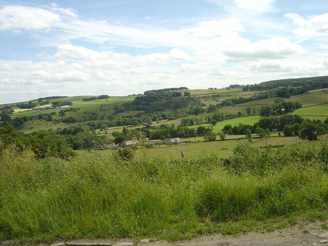Rolling green hills, a small house, and a clear blue sky.