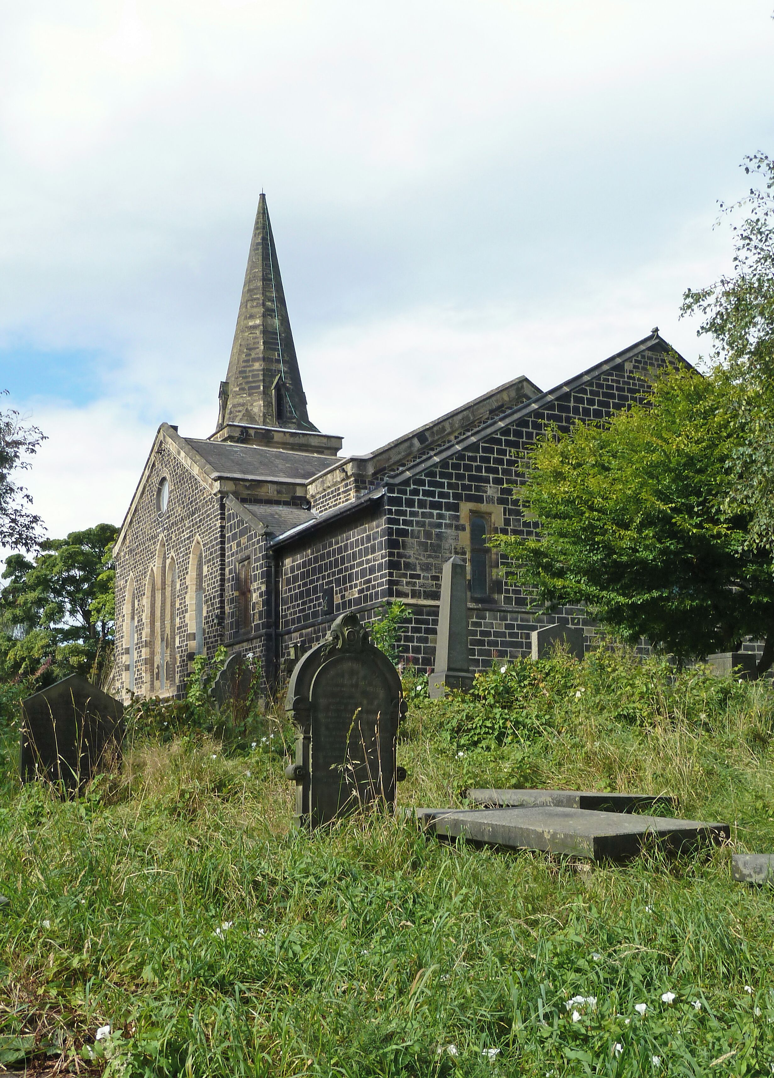 A historic stone church with a pointed steeple and an arched entrance.