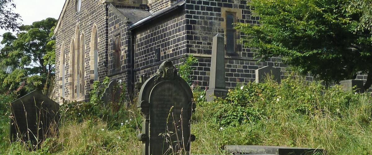 A historic stone church with a pointed steeple and an arched entrance.