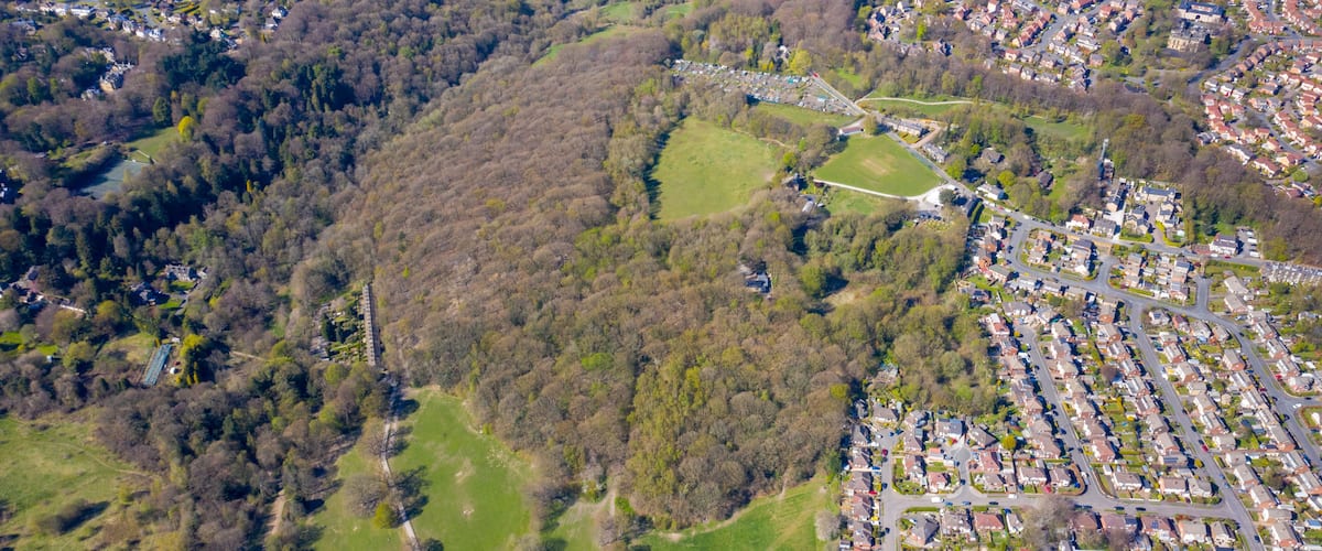 An aerial view of a residential area with a large park, a sports field, and surrounding greenery.