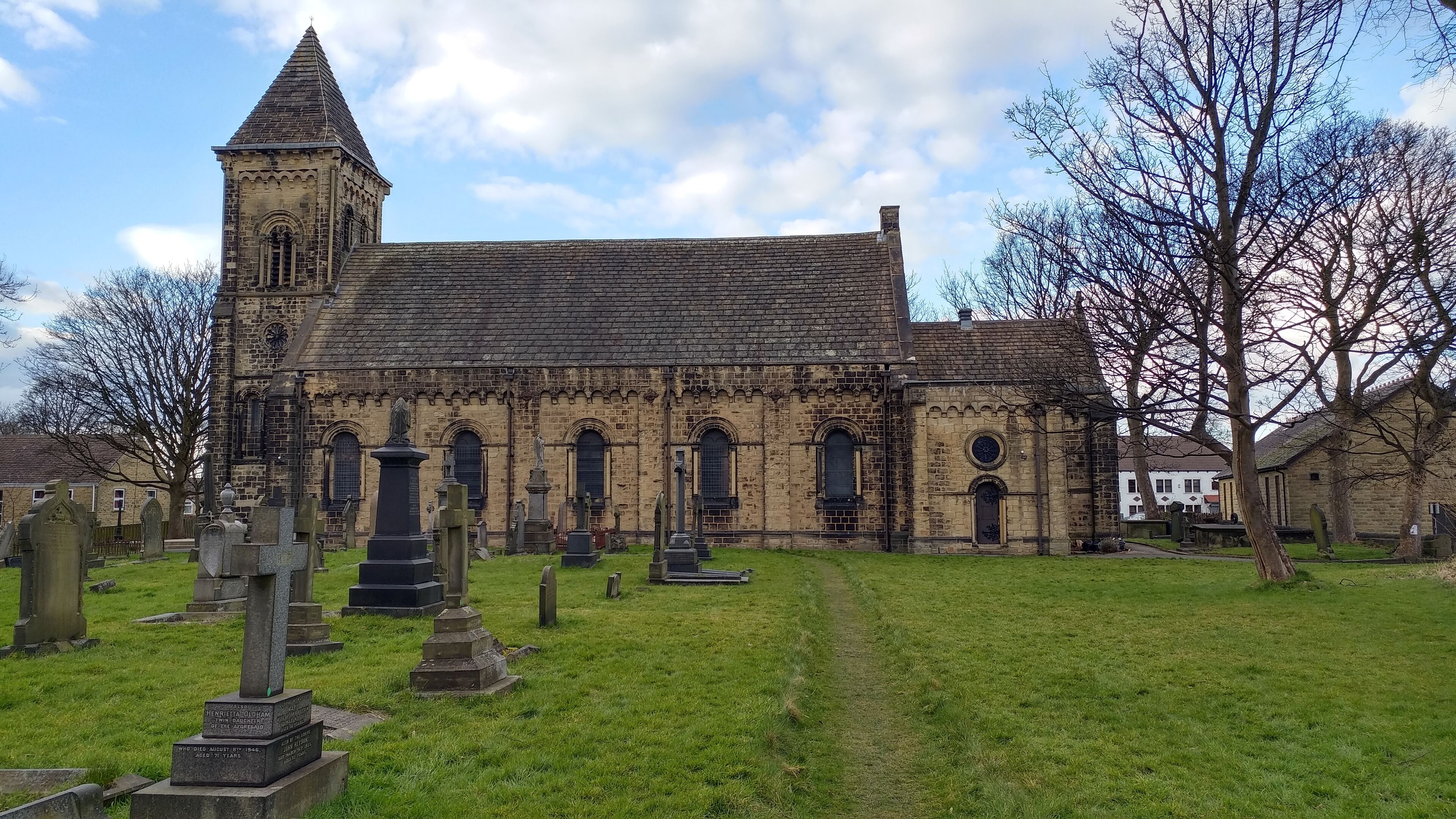 A historic church with a tall tower and a cemetery in front.