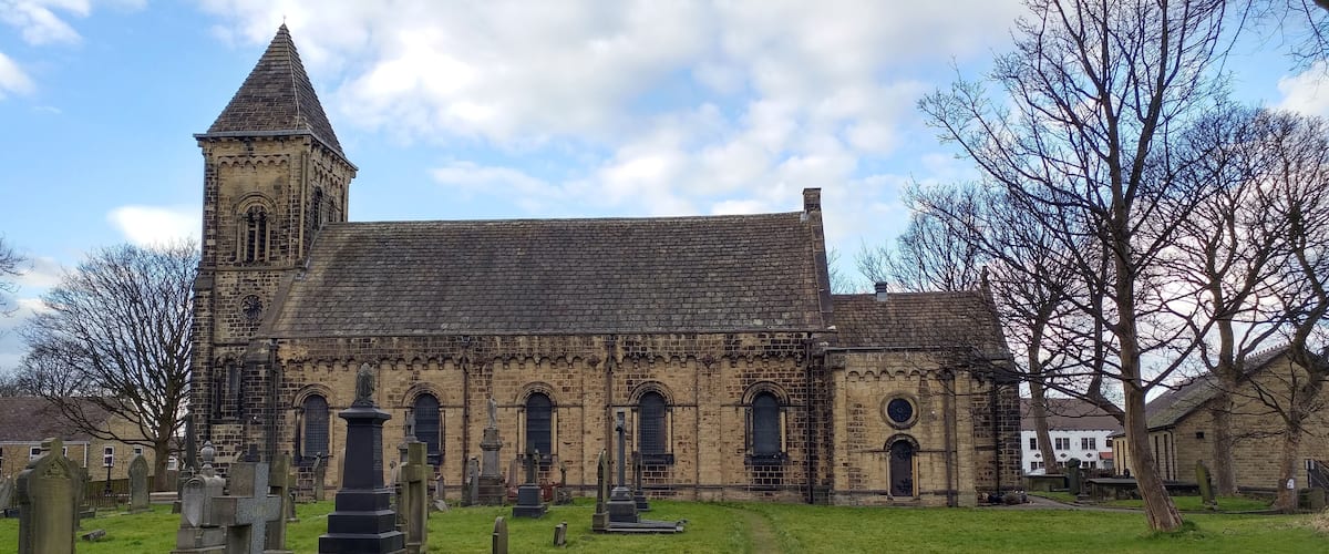 A historic church with a tall tower and a cemetery in front.