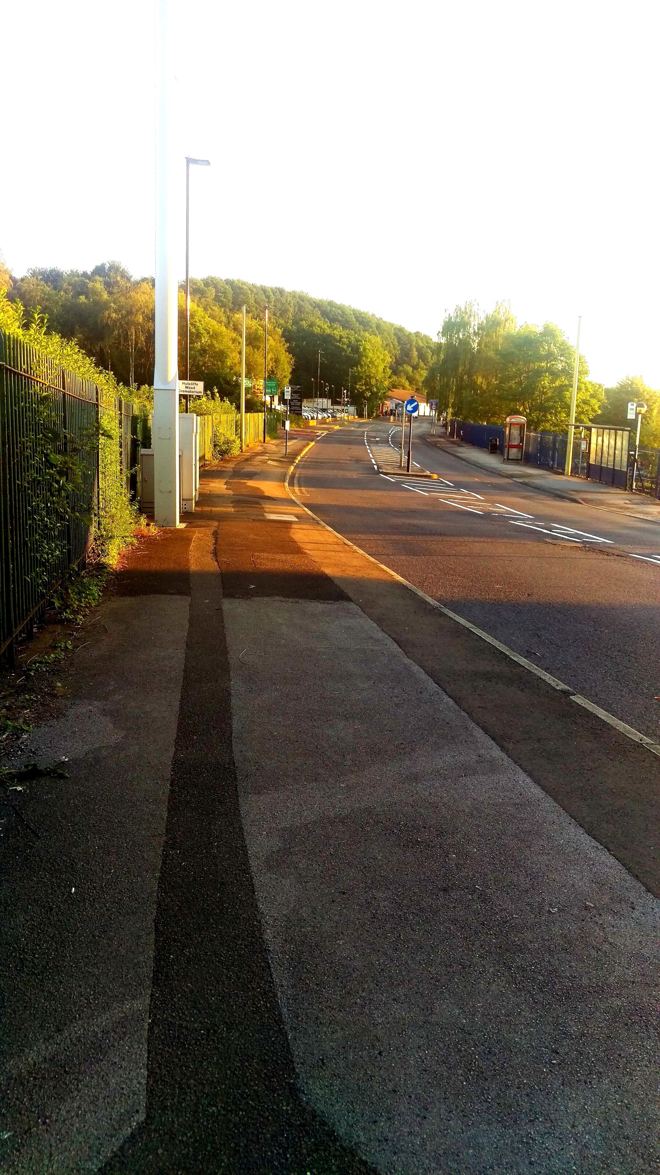 A road with a pedestrian crossing, a bus stop, and a sign indicating a hospital.