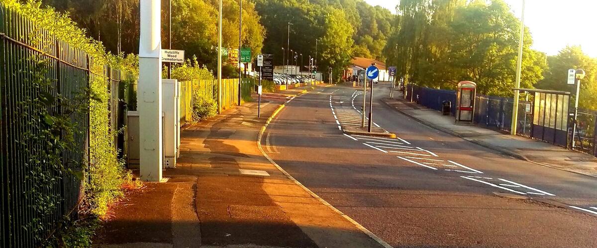 A road with a pedestrian crossing, a bus stop, and a sign indicating a hospital.