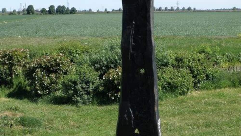 Uma escultura preta com inscrições apontando em diferentes direções.