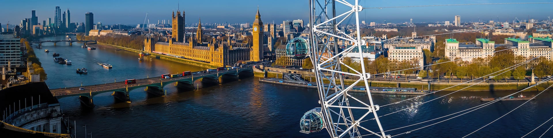 A river with bridges, a Ferris wheel, and historic buildings including the Big Ben clock tower.