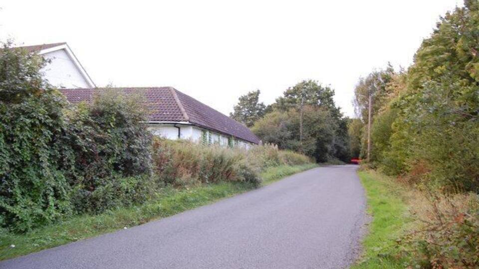 Home Farm Road This view looks north along the road with Home Farm and its outbuilding on the left.
