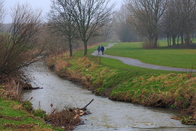 A river with a path and people walking.