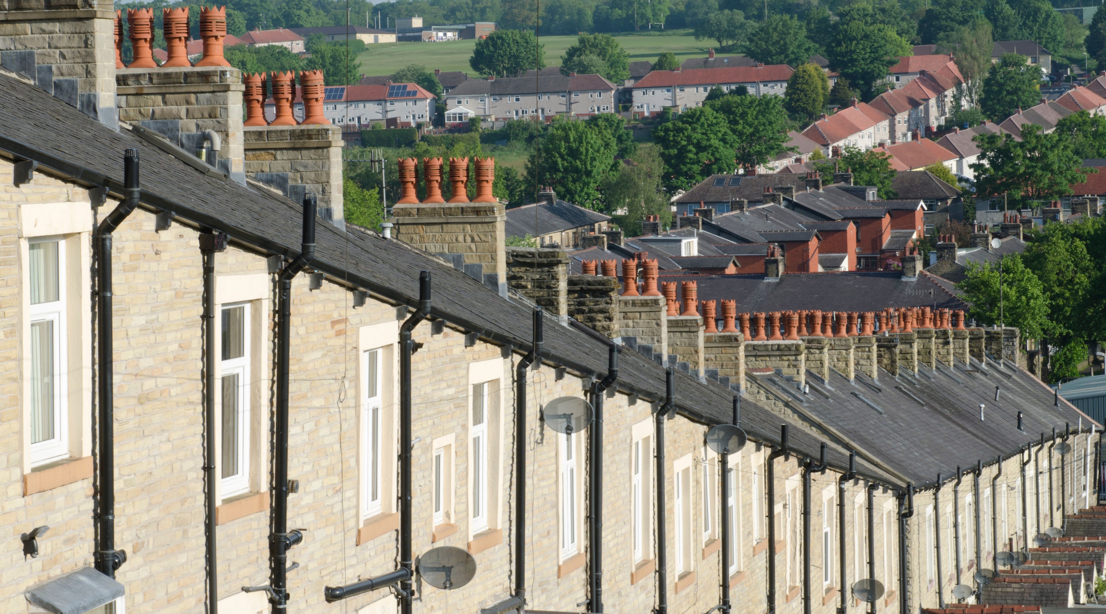 A row of terraced houses with red roofs and brick chimneys.
