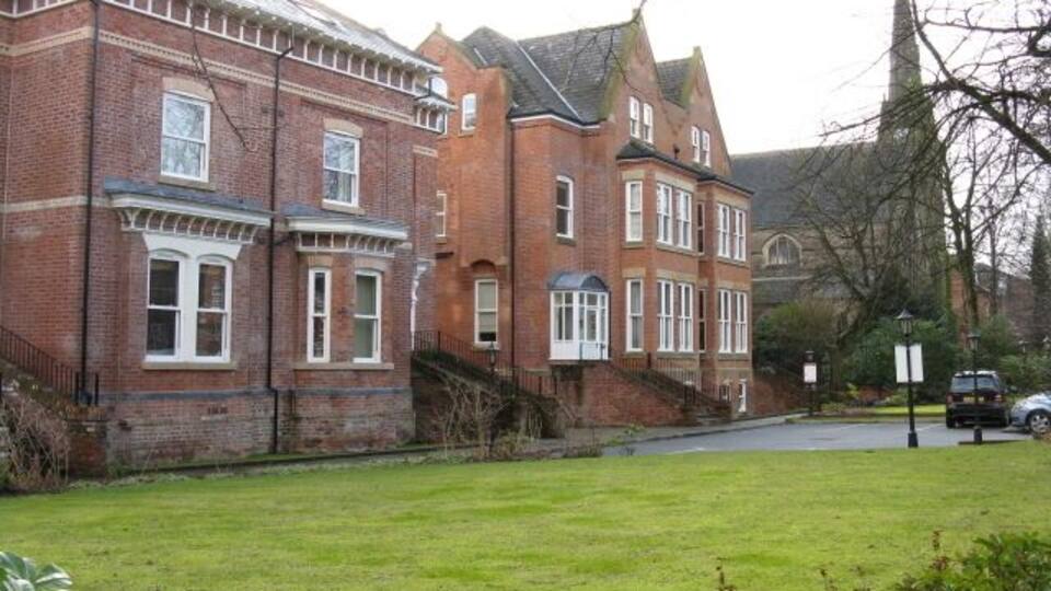 A large brick building with multiple windows and a well-maintained lawn in front.