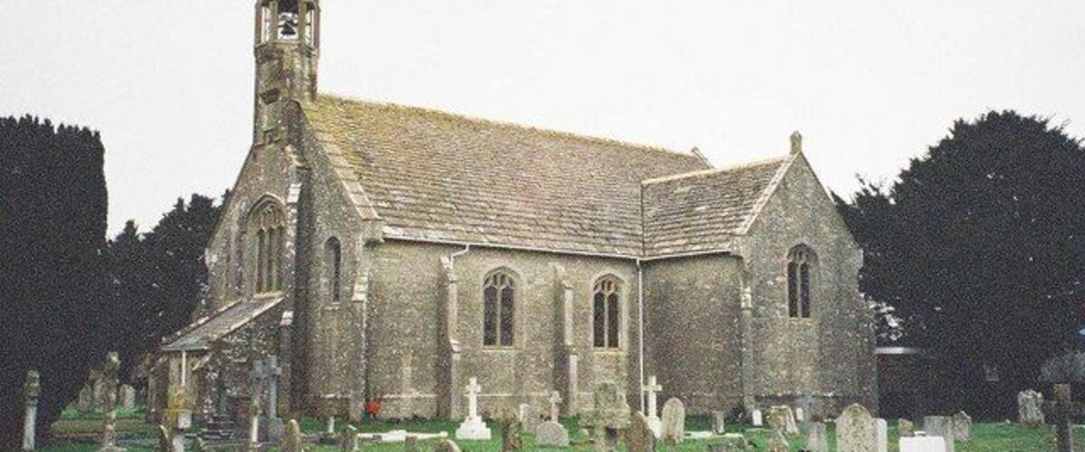 A church with a tall steeple and a graveyard in front.