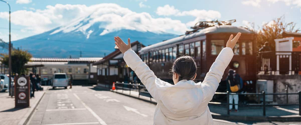 Woman tourist with Fuji Mountain at Kawaguchiko train station, happy Traveler sightseeing Mount Fuji in Yamanashi, Japan. Landmark for tourists attraction. Japan Travel, Destination and Vacation