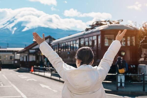 Woman tourist with Fuji Mountain at Kawaguchiko train station, happy Traveler sightseeing Mount Fuji in Yamanashi, Japan. Landmark for tourists attraction. Japan Travel, Destination and Vacation