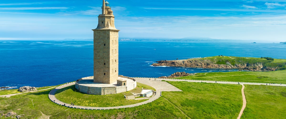 Un faro en una colina cubierta de hierba con vistas al vasto océano.