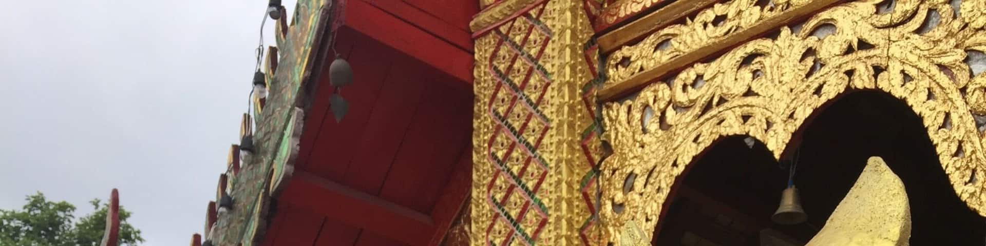 A golden statue of a mythical creature with a white flower garland, colorful ribbons, and a bell.