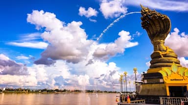 Une statue dorée représentant un serpent, un plan d’eau et un ciel dégagé avec des nuages.