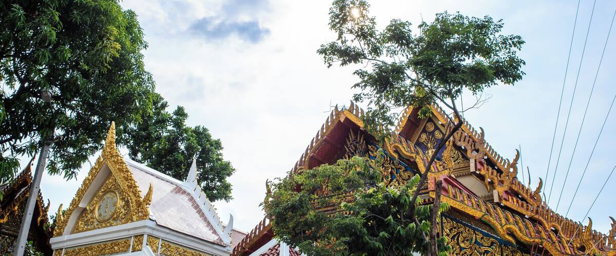 A temple with ornate golden roofs and intricate designs, surrounded by lush green trees.