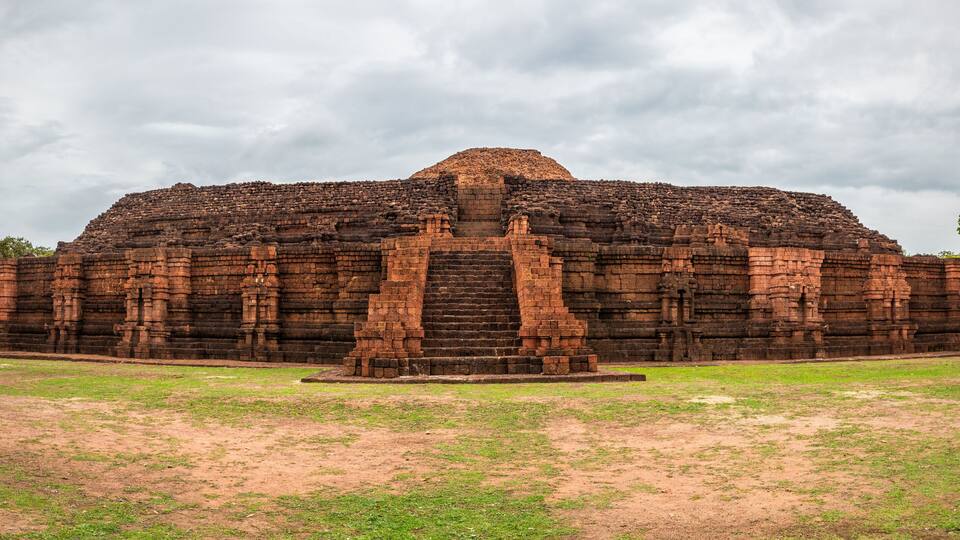 A large, ancient brick temple with a central staircase and a flat-topped structure.