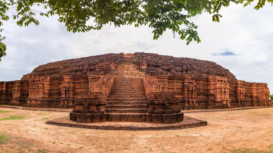 A large, ancient brick structure with a central staircase and a surrounding circular platform.