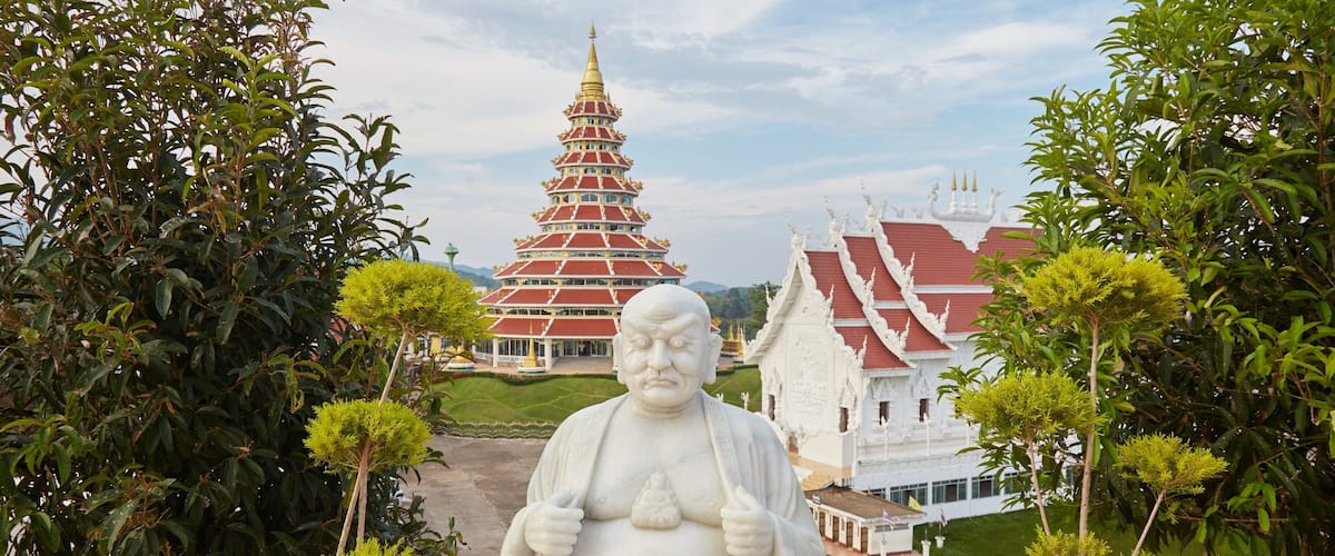 A large Buddha statue in a garden with a pagoda in the background.